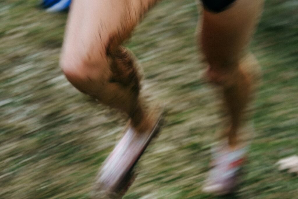 Pernas de um corredor sujas de lama em uma corrida na grama