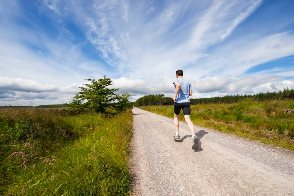 Homem correndo em uma estrada ao lado de um campo
